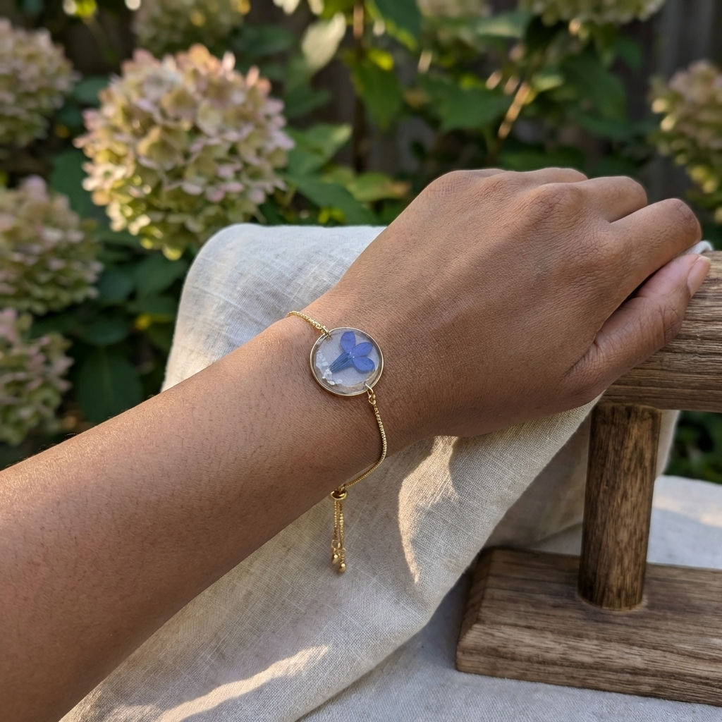 Dark skin tone model wearing a blue lobelia bracelet, showing a vivid contrast with delicate gold plated jewellery