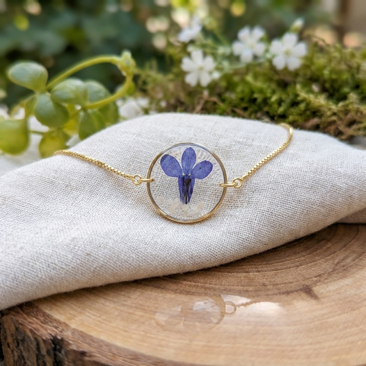 Blue lobelia 20mm flat bracelet with seashell flakes on jewellery display stand, handmade real flower jewellery by Work by Nature