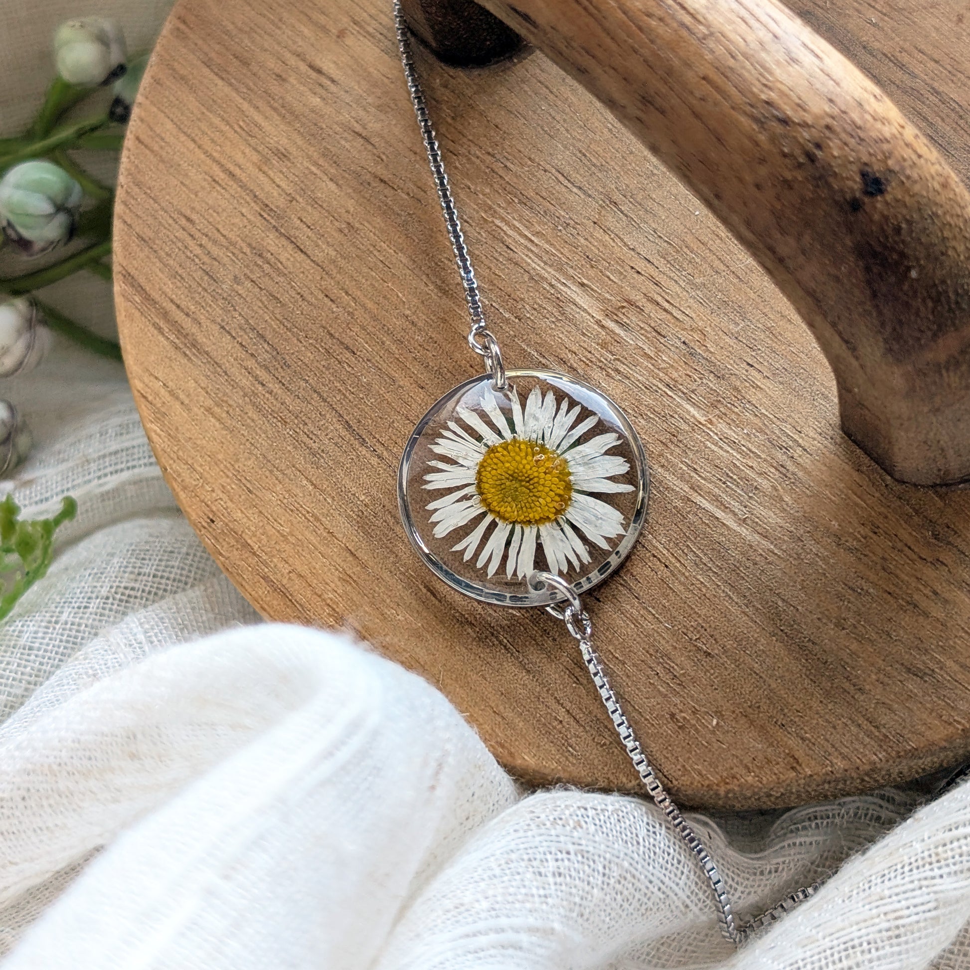Platinum plated daisy bracelet shown on a jewellery holder, crafted with a real daisy preserved in resin