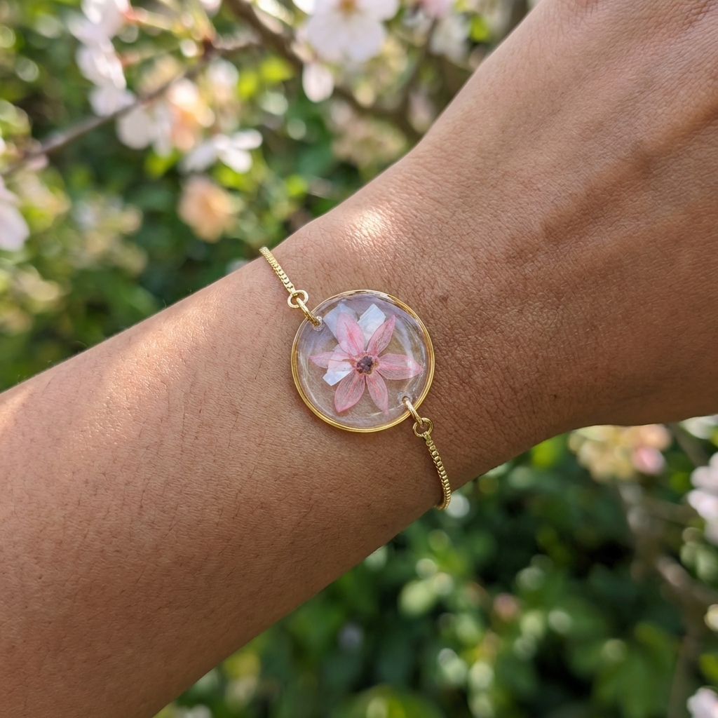 Dark skin tone model wearing a pink chive blossom bracelet, showing a soft contrast with delicate gold plated jewellery