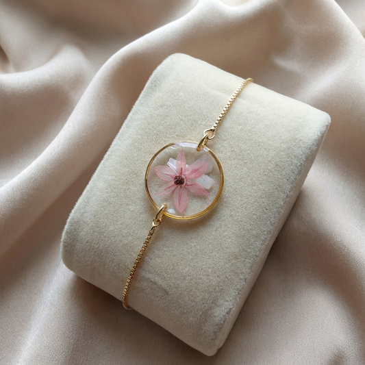 Pink chive blossom 20mm flat bracelet with seashell flakes on jewellery display stand, handmade real flower jewellery by Work by Nature