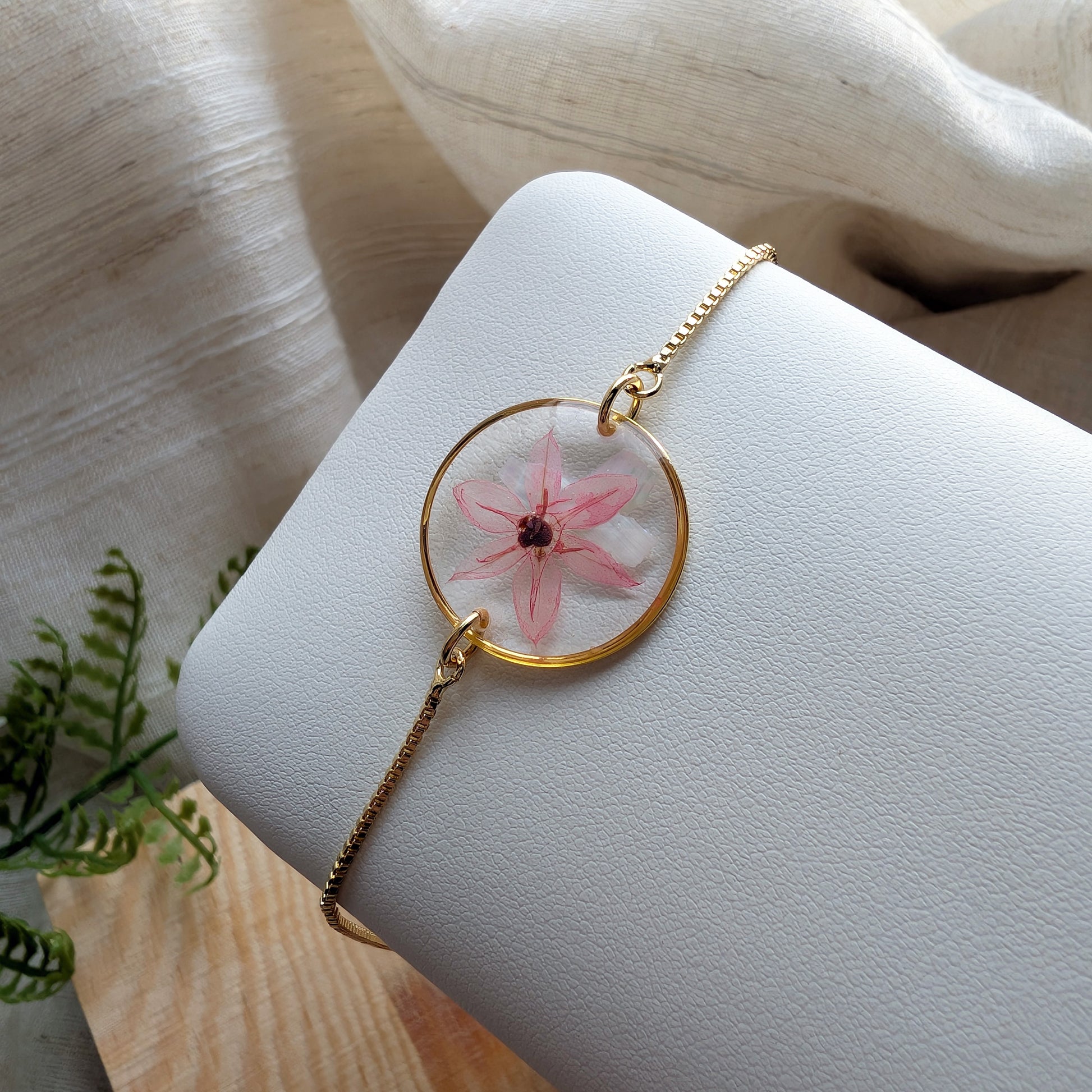 Pink chive blossom 20mm flat bracelet with seashell flakes on jewelry display stand, handmade real flower jewelry by Work by Nature