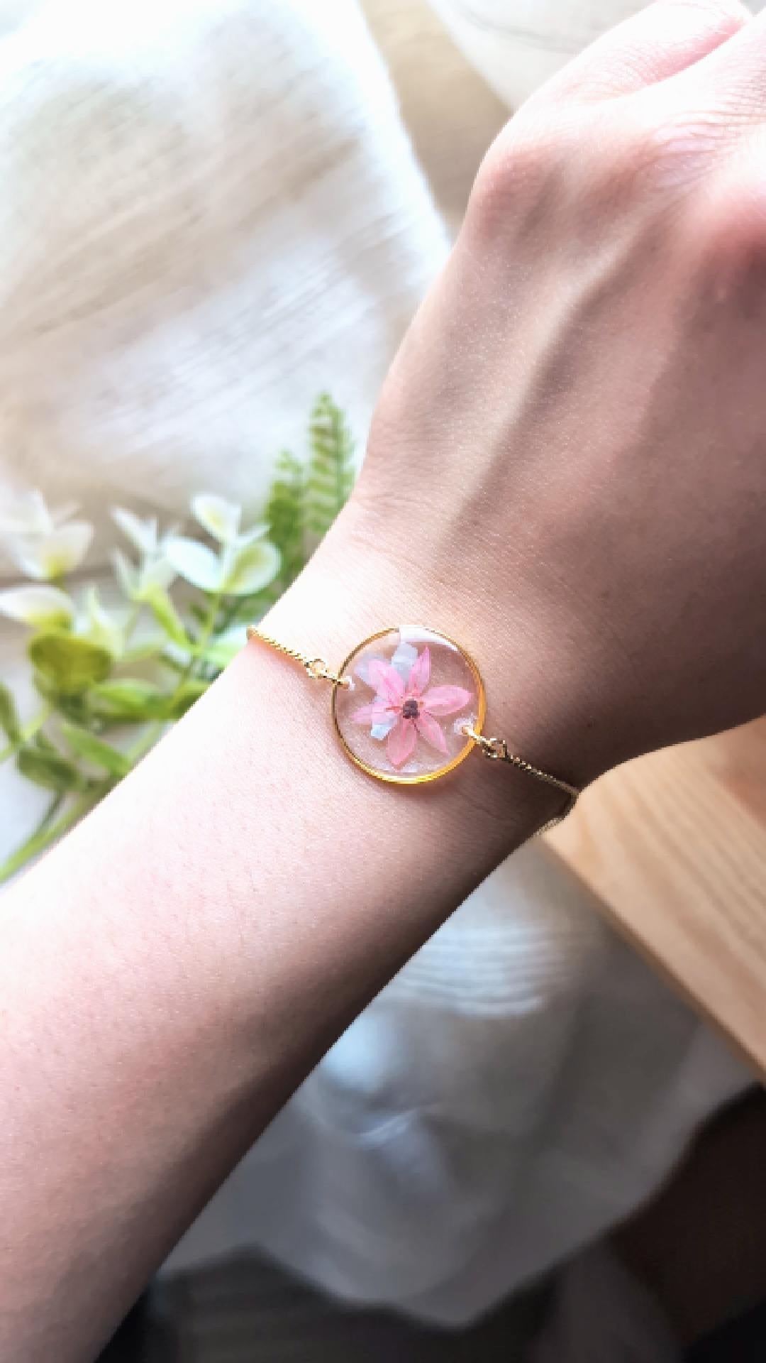 Pink chive blossom 20mm flat gold plated bracelet with seashell flakes, shown in movement to highlight the real flower details and handmade resin finish