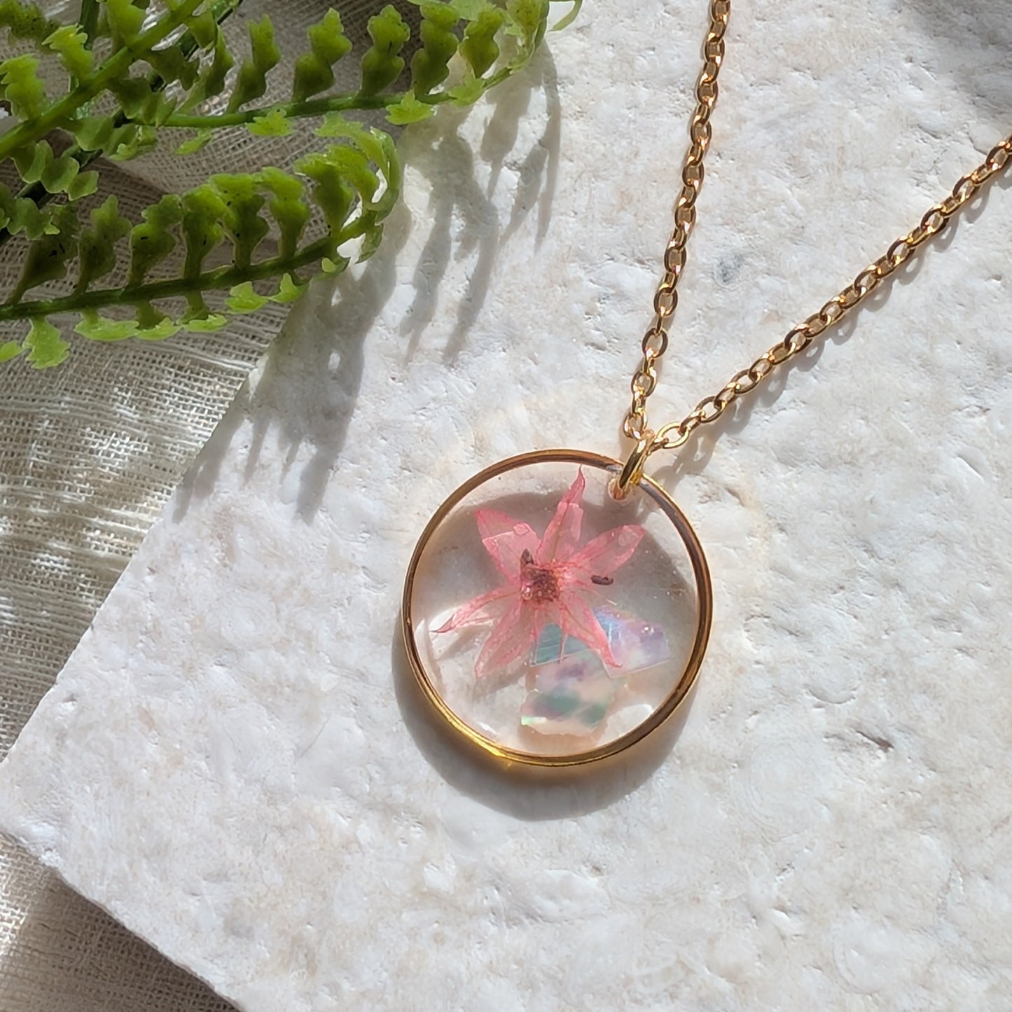 Pink chive blossom 20mm flat necklace with seashell flakes on jewellery display stand, handmade real flower jewellery by Work by Nature