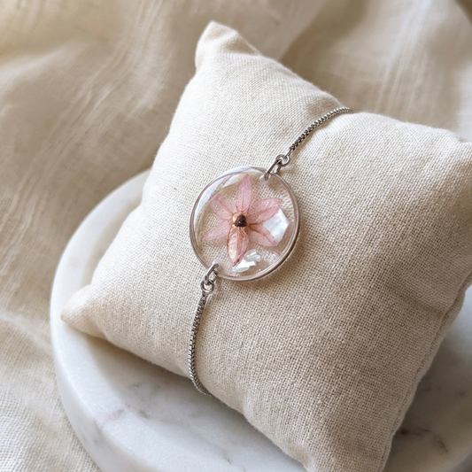 Pink chive blossom 20mm flat bracelet with seashell flakes on jewellery display stand, handmade real flower jewellery by Work by Nature