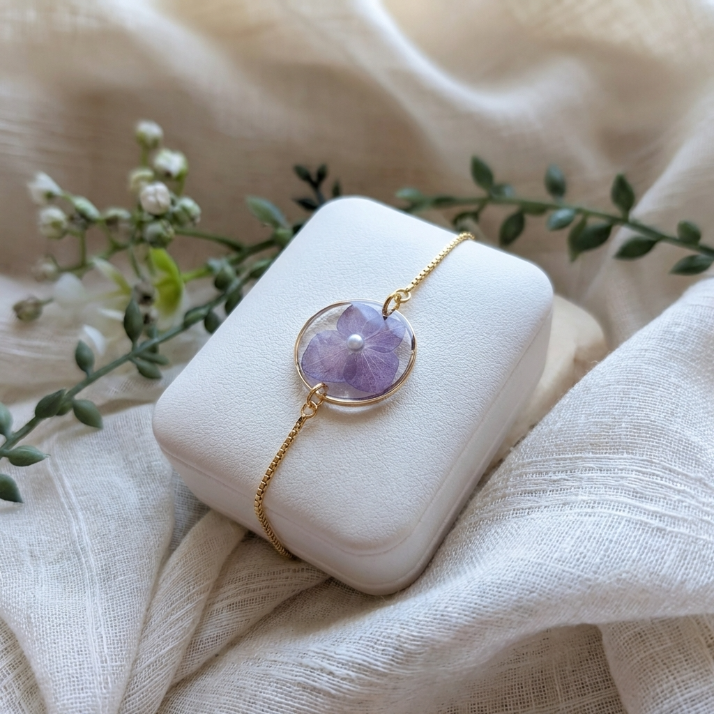 Gold plated purple hydrangea bracelet shown on a jewellery holder, crafted with real flowers, resin and an imitation pearl centre