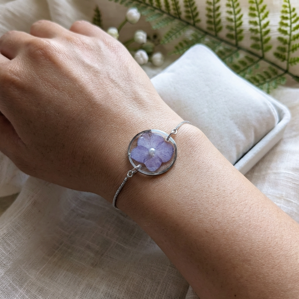 Dark skin tone model wearing a purple hydrangea bracelet, showing a soft contrast with delicate platinum plated jewellery