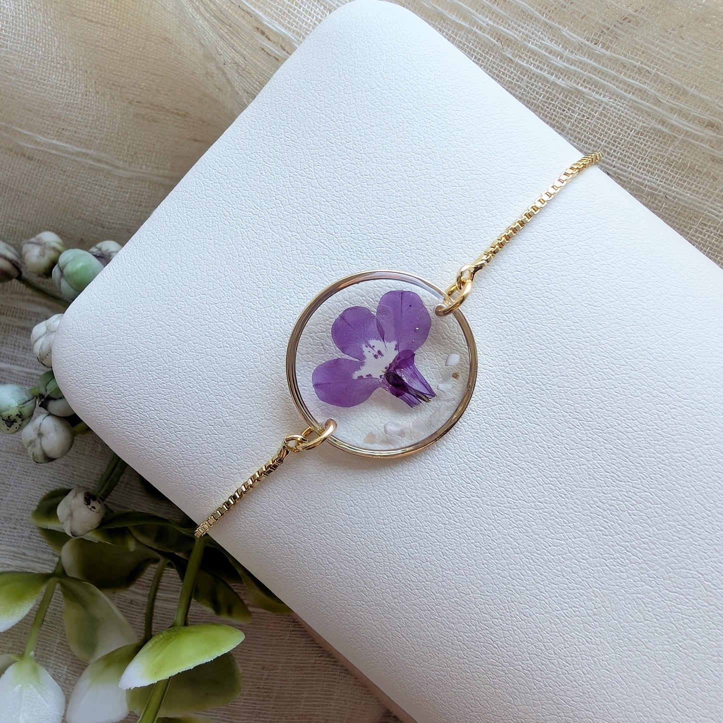 Fair skin model wearing purple lobelia jewelry bracelet, handmade with garden grown flowers preserved in resin