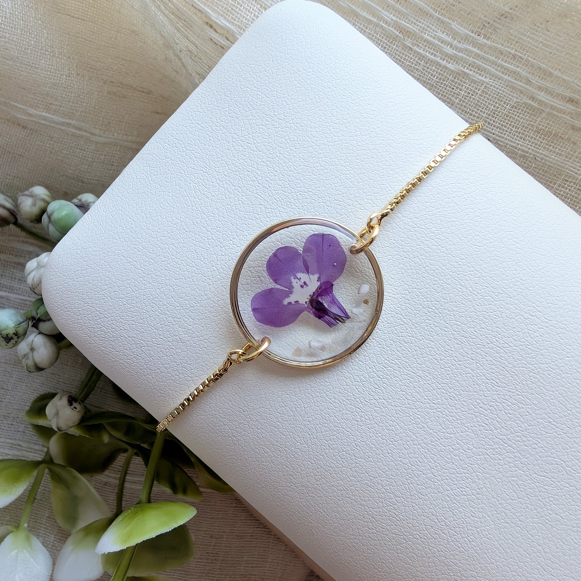 Fair skin model wearing purple lobelia jewelry bracelet, handmade with garden grown flowers preserved in resin