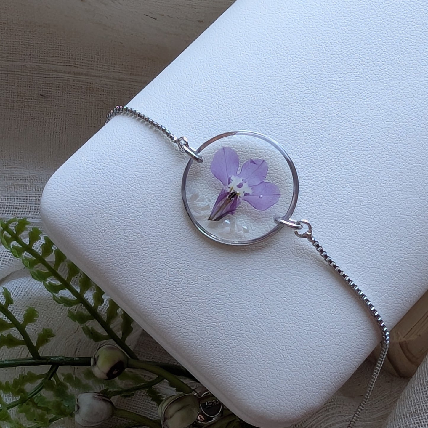 Purple lobelia 20mm flat bracelet with seashell flakes on jewelry display stand, handmade real flower jewelry by Work by Nature