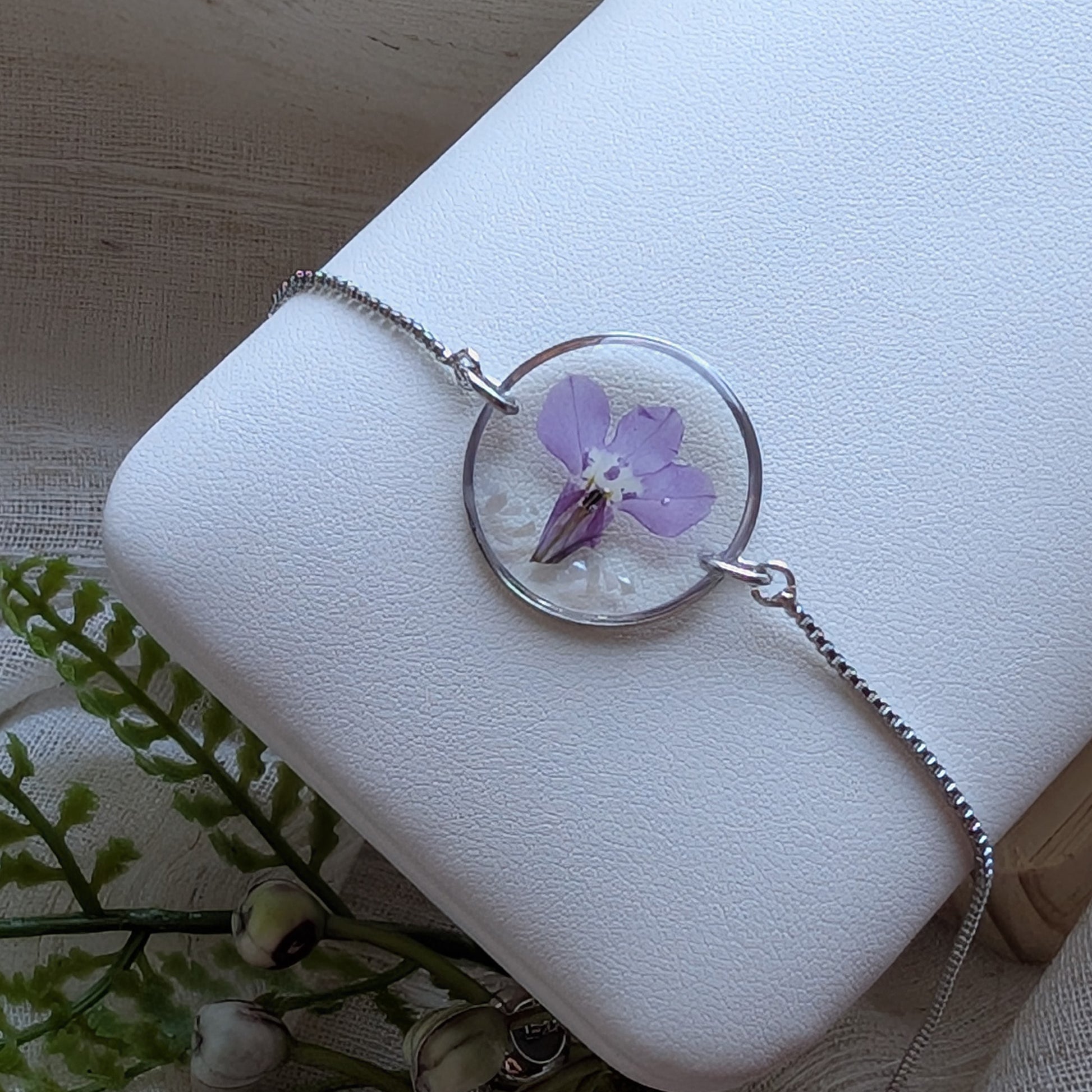 Purple lobelia 20mm flat bracelet with seashell flakes on jewelry display stand, handmade real flower jewelry by Work by Nature