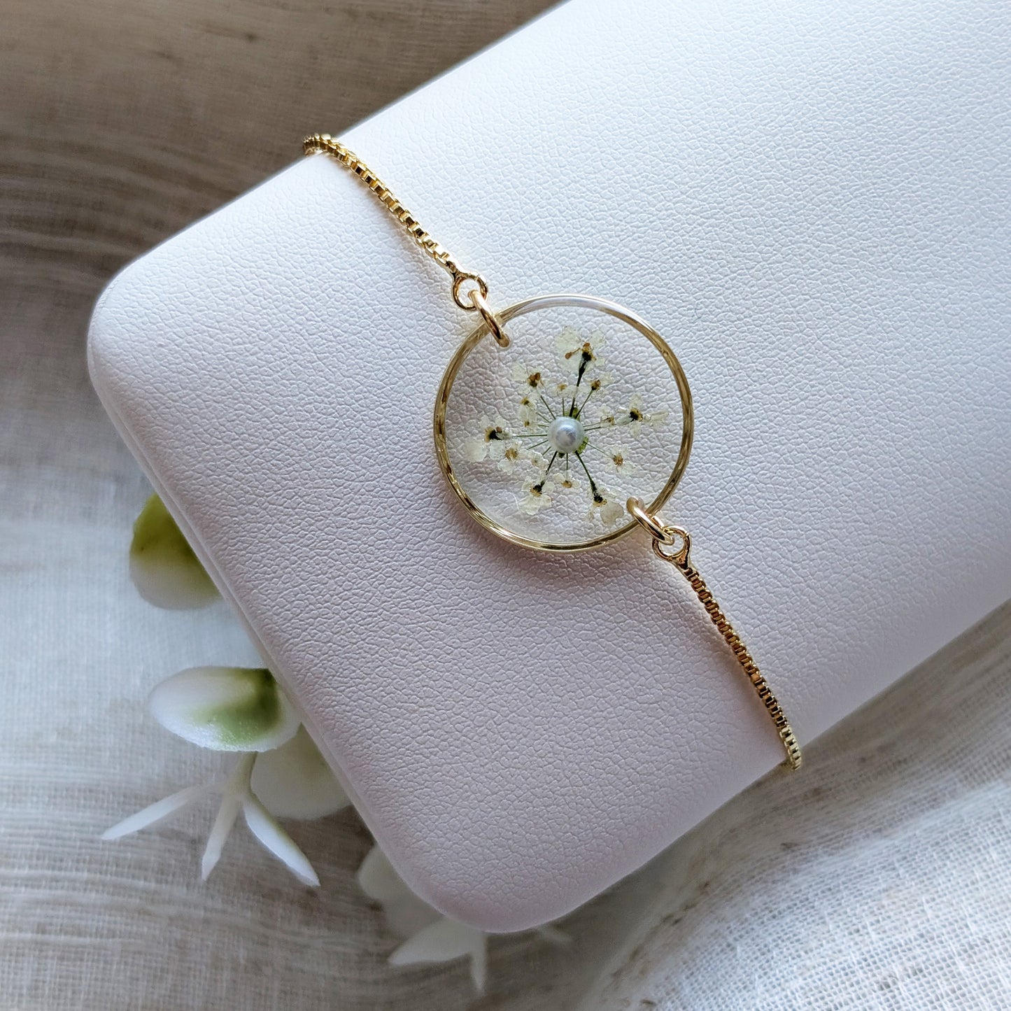 Gold plated Queen Anne’s Lace bracelet shown on a jewellery holder, crafted with real wildflowers preserved in resin