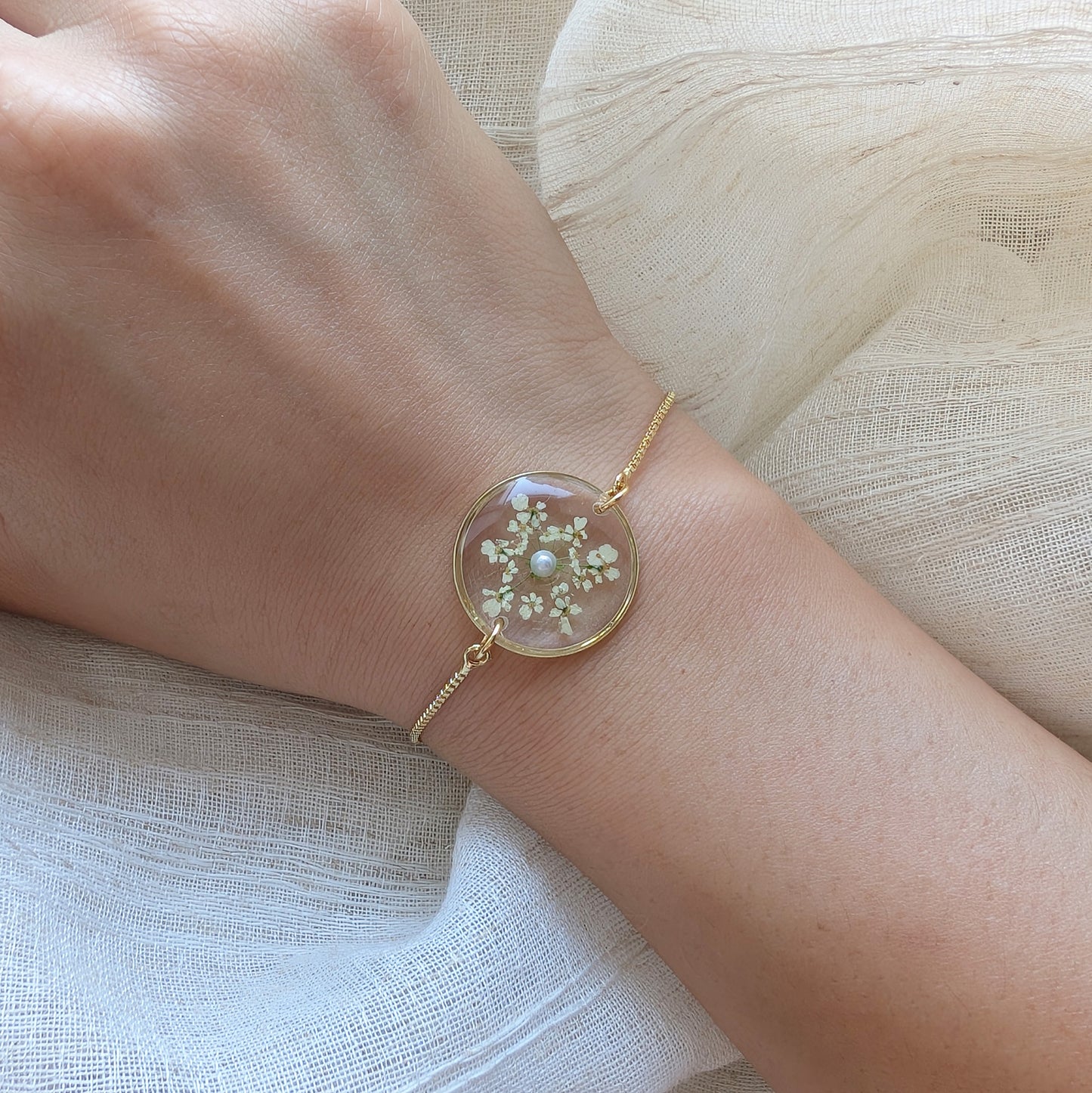Model with fair skin wearing a Queen Anne’s Lace 20mm flat bracelet, delicate gold plated real flower jewellery for everyday wear