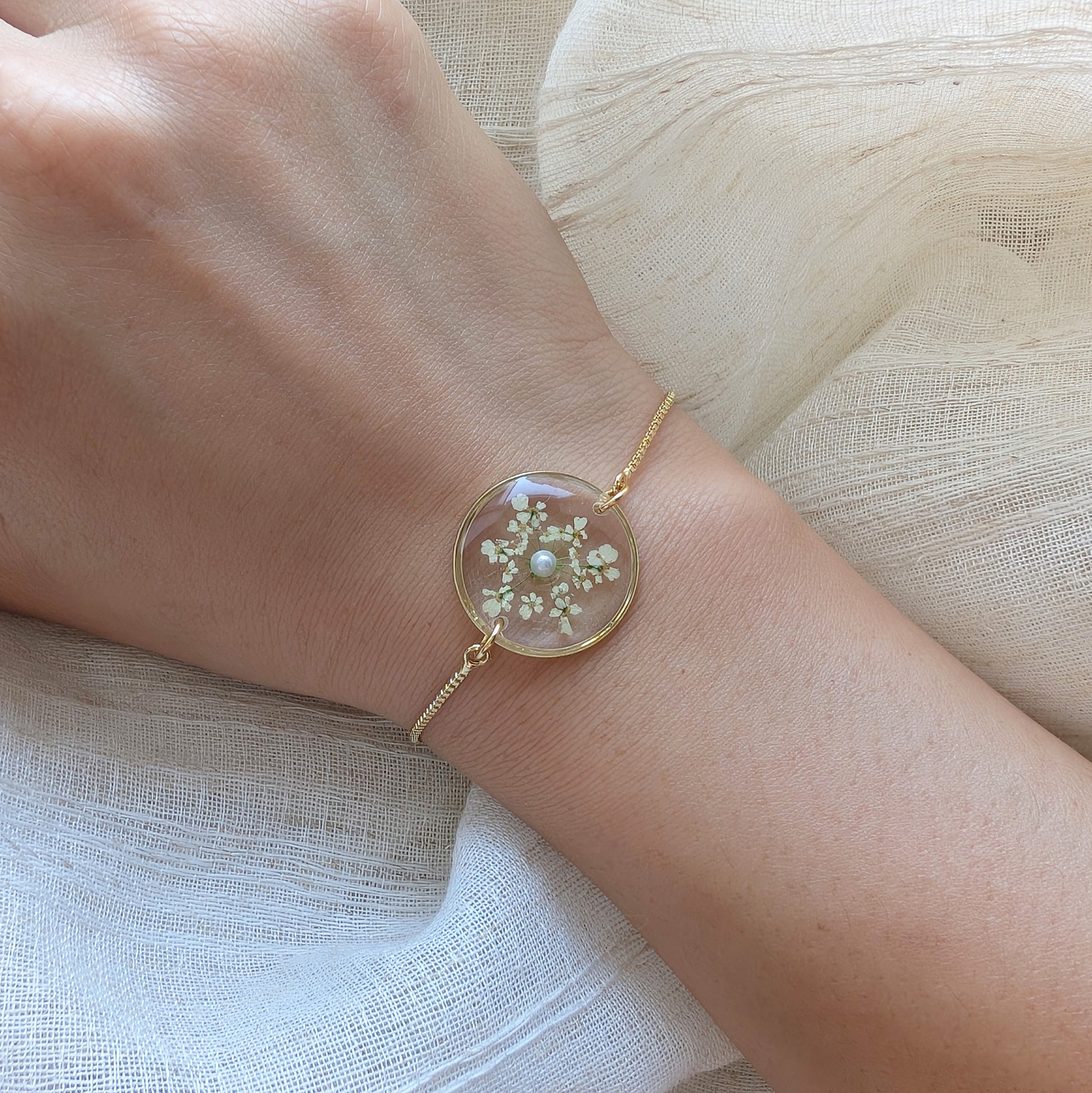 Model with fair skin wearing a Queen Anne’s Lace 20mm flat bracelet, delicate gold plated real flower jewellery for everyday wear