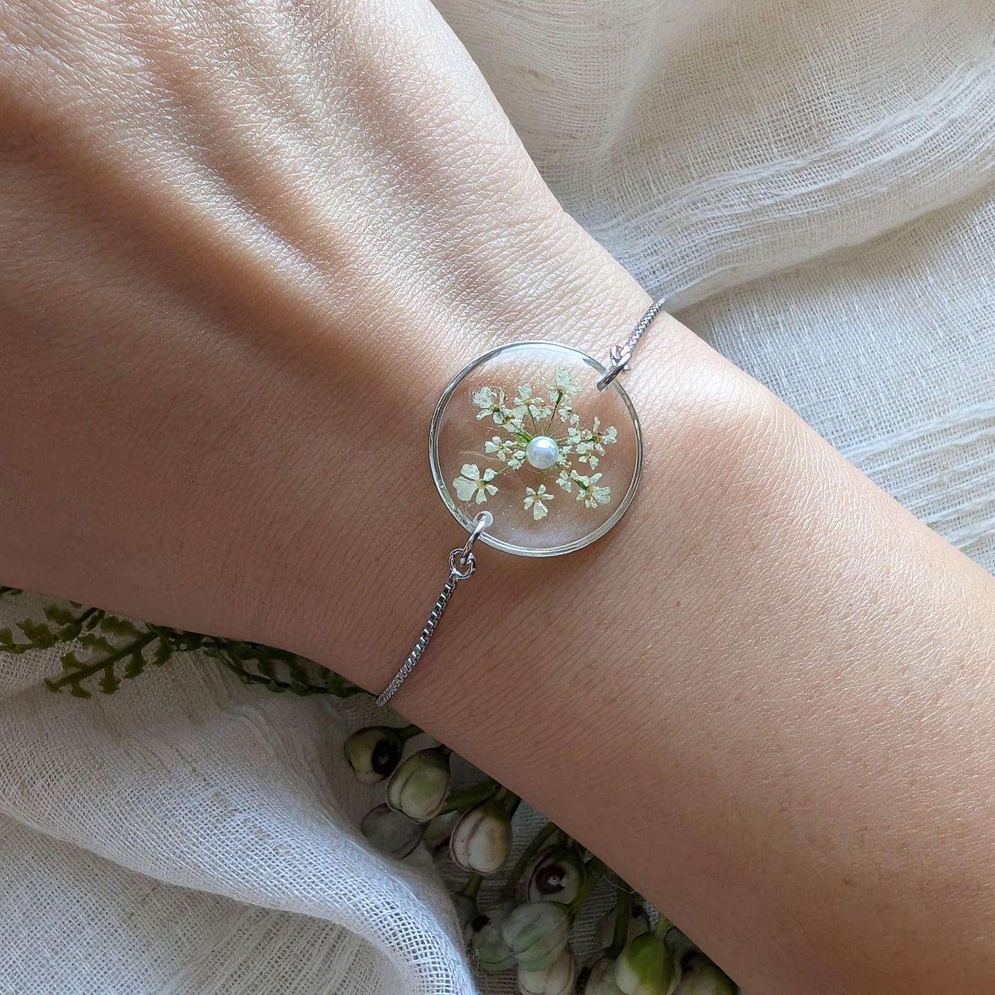 Model with fair skin wearing a Queen Anne’s Lace 20mm flat bracelet, delicate platinum plated real flower jewellery for everyday wear