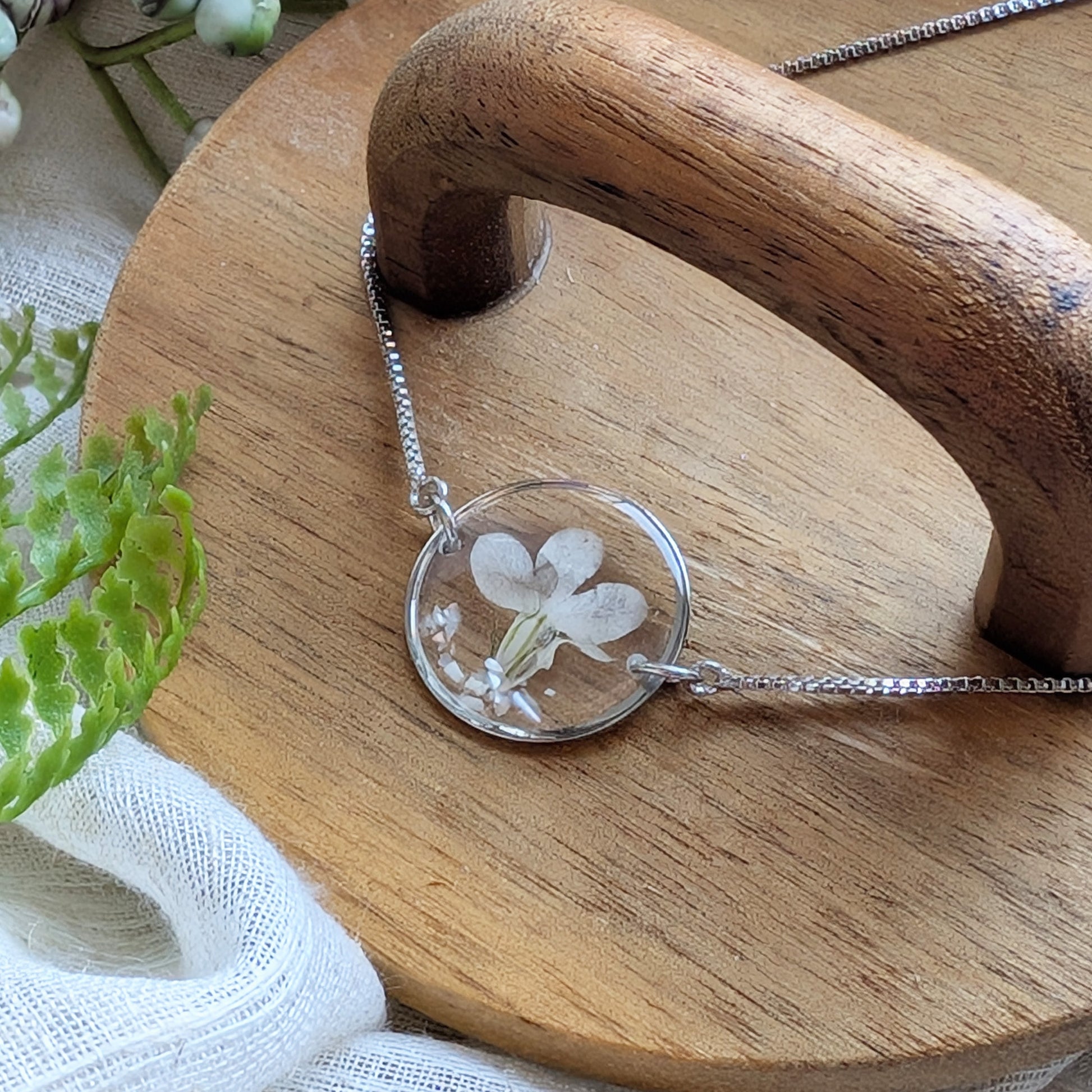 White lobelia 20mm flat bracelet with seashell flakes on jewellery display stand, handmade real flower jewellery by Work by Nature
